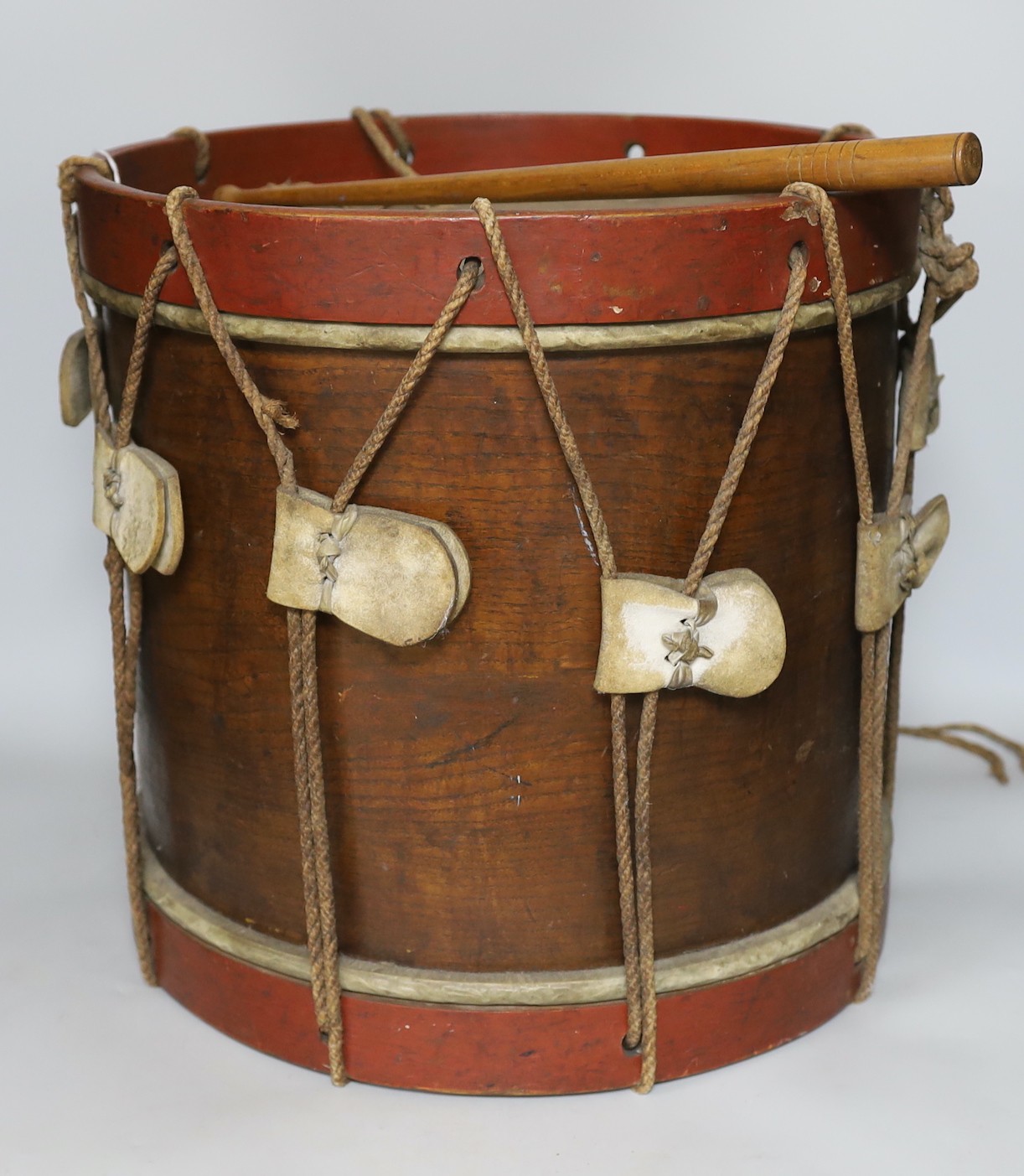 An elm and brass studded drum, with painted bands and a drum stick